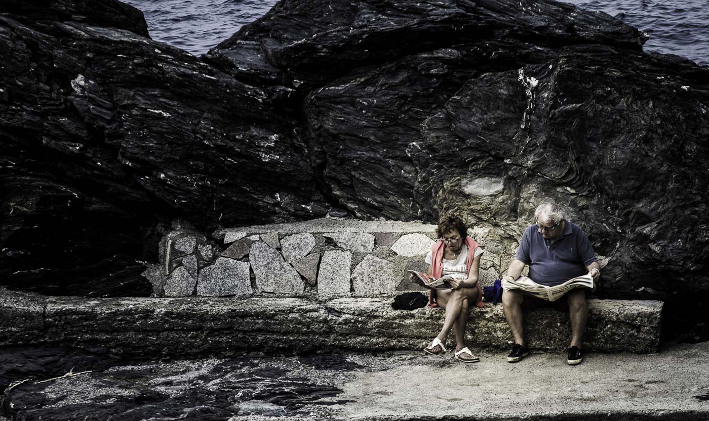 Old couple reading by the sea